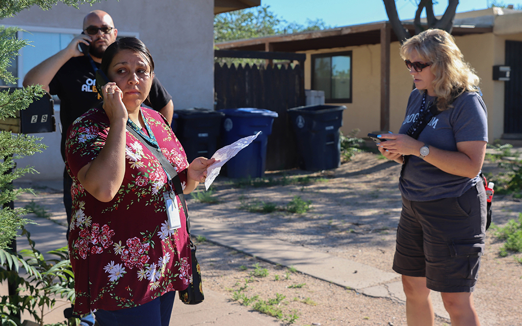 Elaine Maestas, left, a community oriented response and assistance responder in Albuquerque, New Mexico, makes a phone call alongside Albuquerque Community Safety responders Chris Blystone and Deborah Vigil on July 7, 2022. They responded to the aftermath of a SWAT raid that left a family of five without a home. (Photo by Kate Heston/News21)