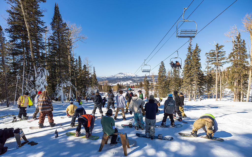 Contestants at the “The Site” snowboarding and ski competition wait to do a run down Sunset Terrain Park on Jan. 28, 2023. Collective Supply Co., a clothing brand geared toward the Flagstaff snowboarding community, co-hosted the competition with the park. “Snowboarding is growing at a huge rate and obviously we are stoked on that,” said Rich Phillips, co-founder of Collective Supply Co. “Snowboarding is definitely alive and kicking, especially in AZ.” (Photo by Drake Presto/Cronkite News)