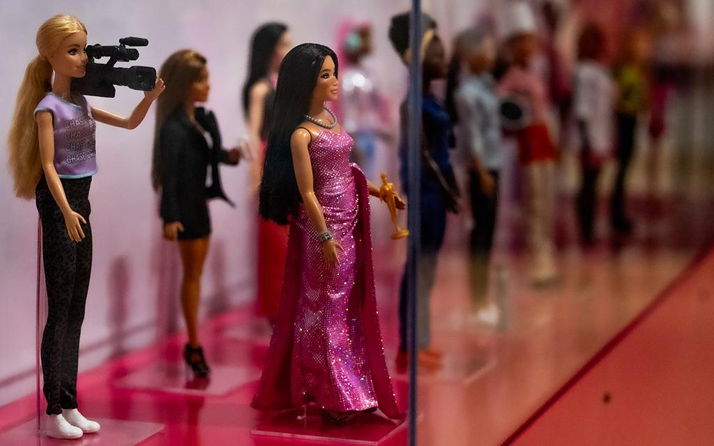A display case at the “Barbie: A Cultural Icon” exhibition at the Phoenix Art Museum shows off some of the many career Barbies, including a camerawoman Barbie and an award-winning actress Barbie. Throughout her existence, Barbie has taken on more than 250 different careers. Photo taken in Phoenix on Feb. 21, 2024. (Photo by Emily Mai/Cronkite News)