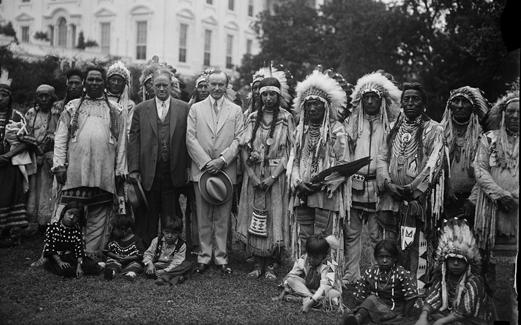 Calvin Coolidge, center in a white suit, poses with a group of Native Americans outside the White House in 1927. (Photo courtesy of Library of Congress)