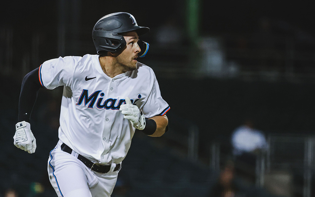 Baseball player in a "Miami" uniform running during a game at night.