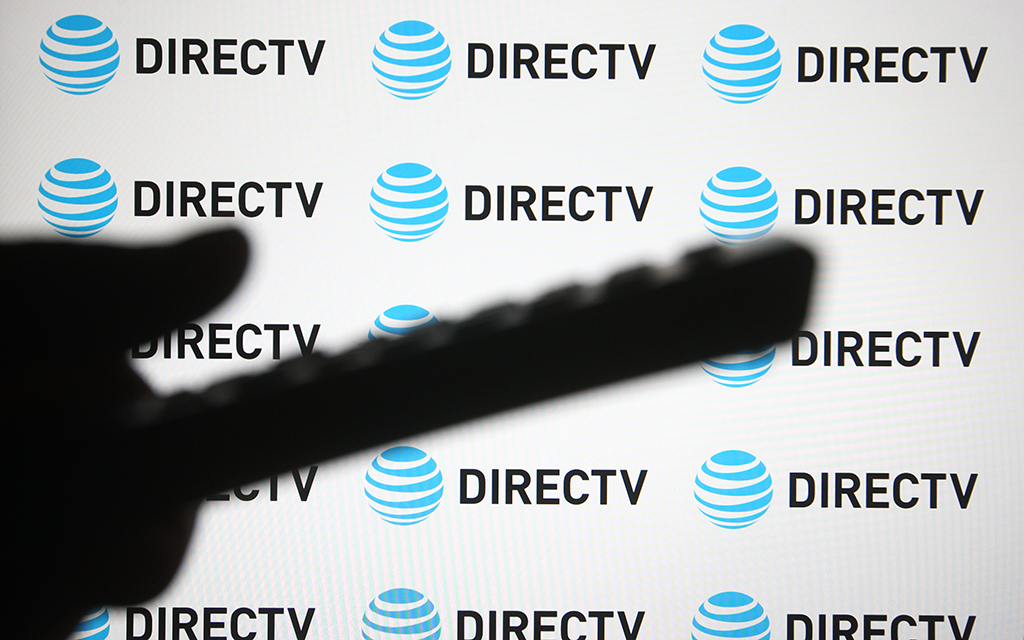 Silhouette of a remote control against a background of repeating DIRECTV and AT&T logos.