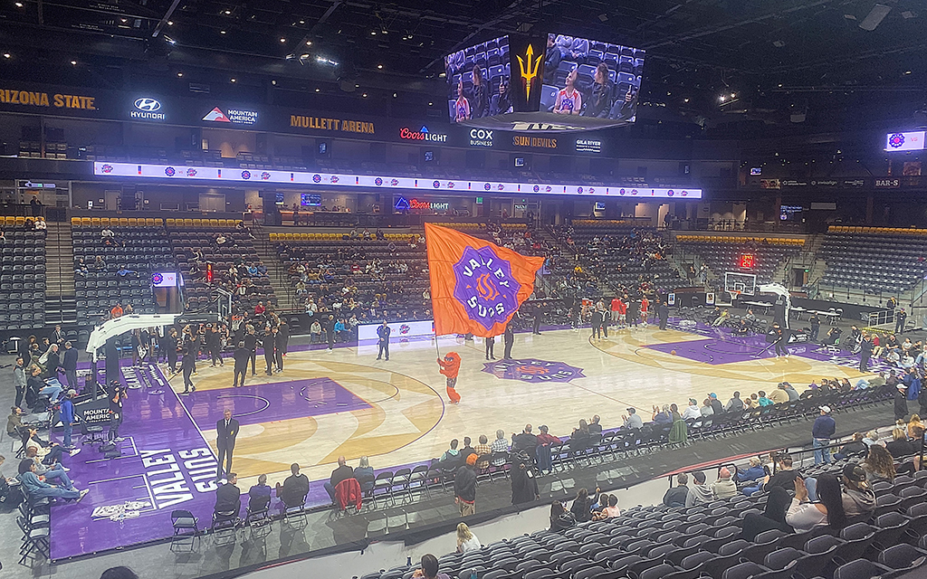 Basketball court in Mullett Arena with a large orange flag at center court and multiple advertisements displayed.