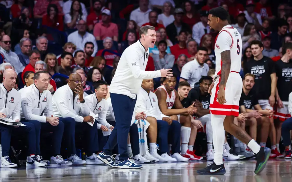 Arizona basketball coach Tommy Lloyd talks to player on court in front of bench