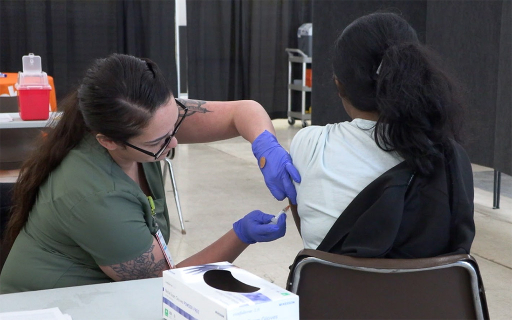 Healthcare worker administering a vaccine to a person in a clinic setting.