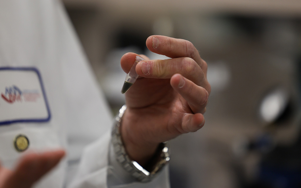 Frederic Zenhausern holding a small vial with a dark green substance.
