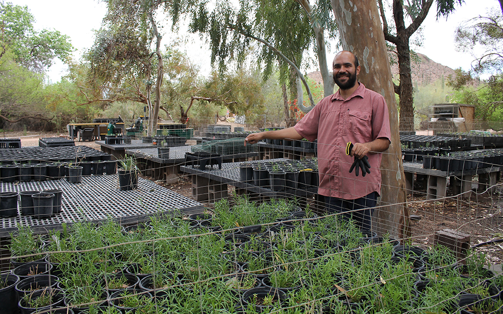 Ricardo Garcia in a plant nursery with pots on platforms and trees in the background.