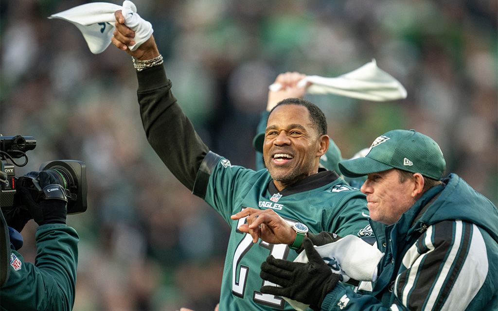 Eric Allen in green sport jersey celebrating in a crowded stadium.