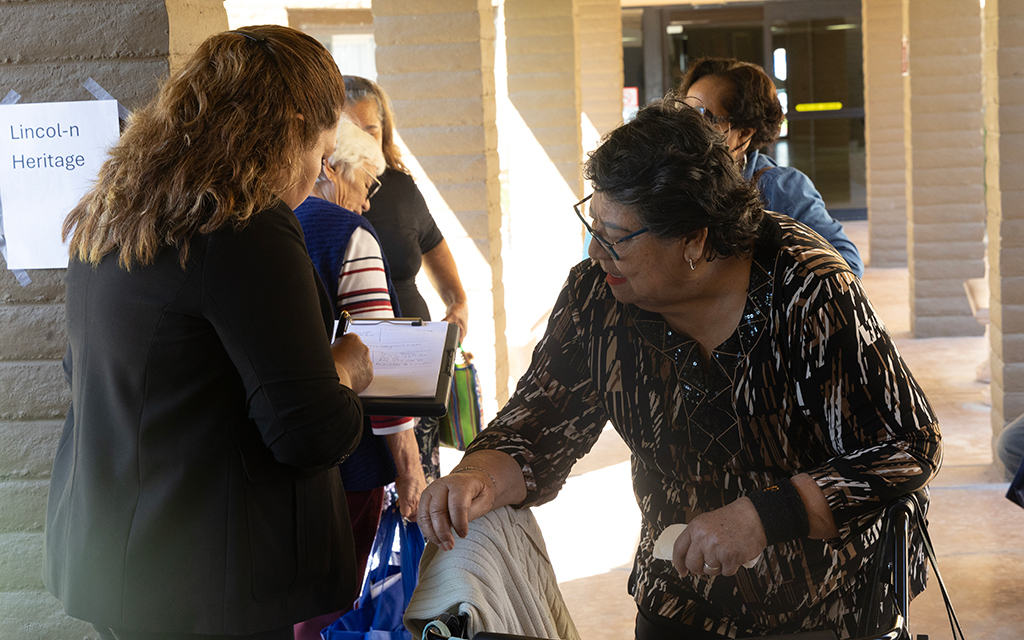 People in a corridor during an event, one signing a clipboard.