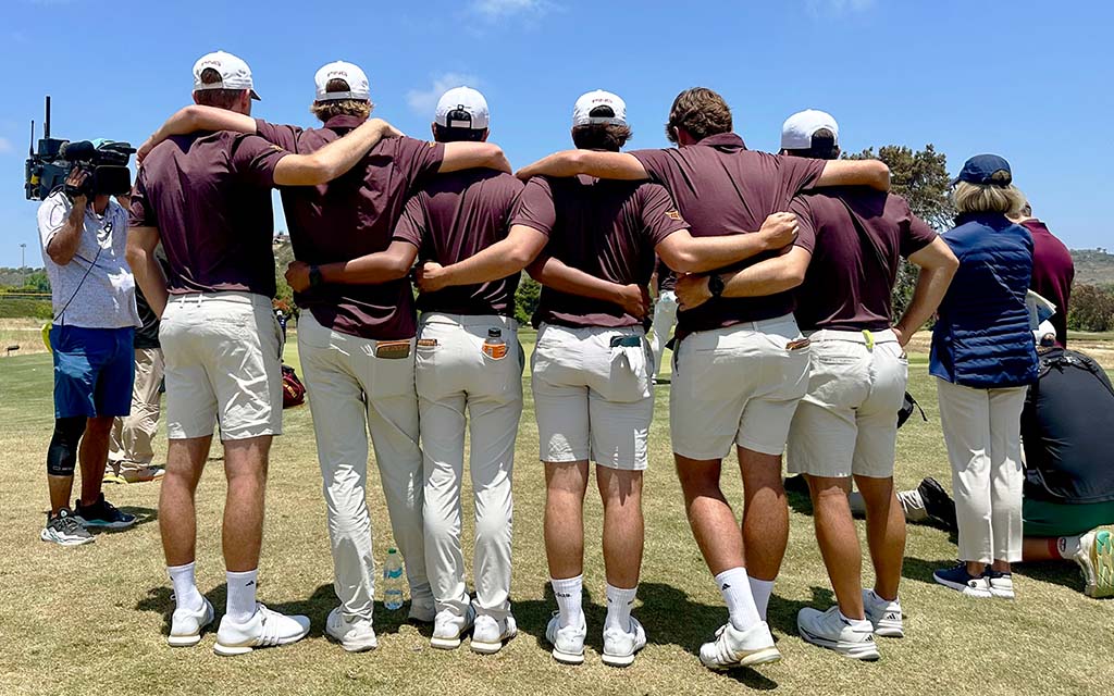 ASU men's golf with arms around each other on a sunny golf course.