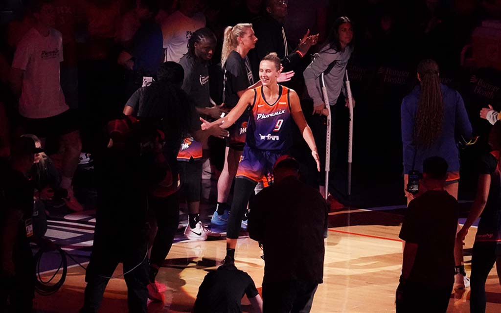 Kitija Laksa high-fiving on a dimly lit court.