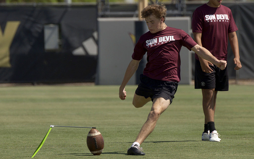 Class of 2027’s third-ranked kicker Mikey Barth kicks an American football on a grassy field.