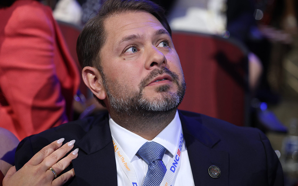 Ruben Gallego in a navy suit looking in the distance with a hand on his shoulder.