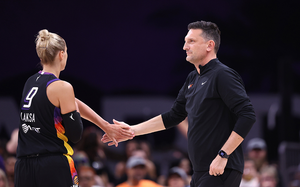 Basketball player and coach exchanging a handshake on the court.