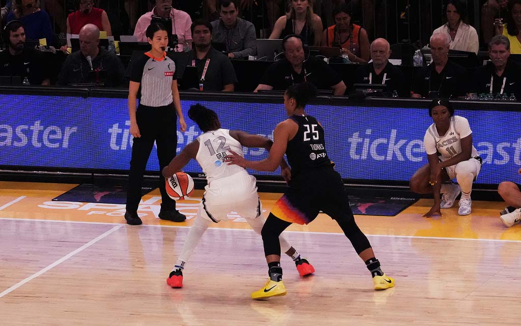 Chelsea Gray and Alyssa Thomas in action on the court, one dribbling and the other defending, with spectators and officials in the background.